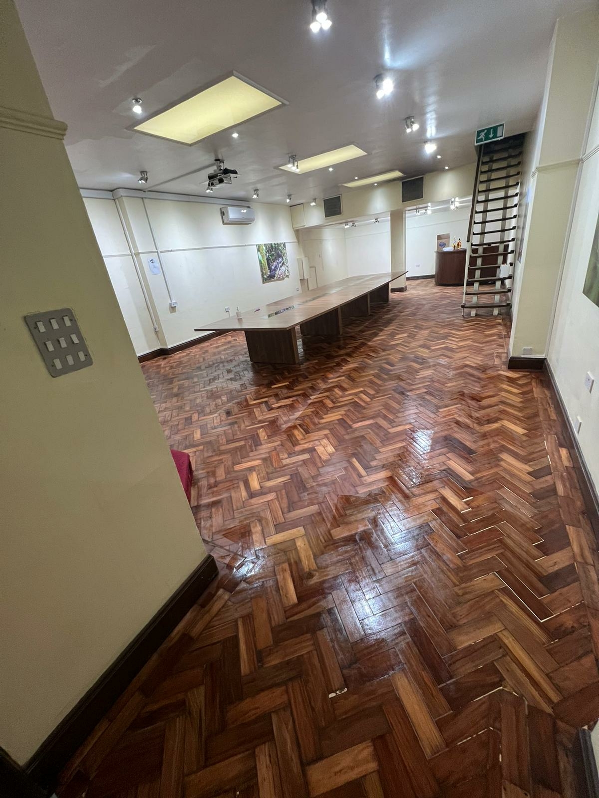 Completed parquet floor restoration at Trafalgar Square corridor — fresh lacquer finish